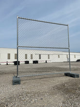 Temporary chain link fence panel set up outdoors with a durable galvanized steel frame and weighted bases, ideal for construction sites and event security.